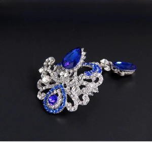 Detail of vintage crystal brooch with blue teardrop stones and rhinestone scrollwork