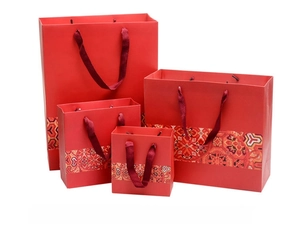 Set of four red Chinese style paper gift bags in varying sizes with silk ribbon handles