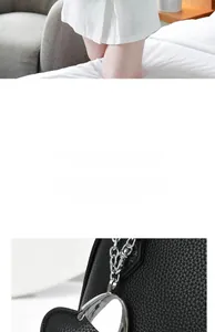 Detail of silver heart-shaped metal pendant on black lychee grain leather tote bag