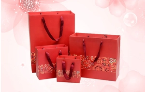 Detail of four red traditional paper gift bags in varying sizes with elegant silk handles