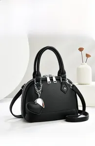 Detail of black litchi grain leather tote bag featuring heart charm and silver zippers
