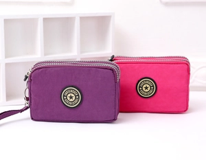 Dettaglio di due borsellini in nylon con tre cerniere nei colori viola e rosa rosso