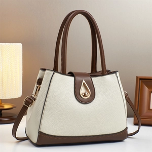 Gros plan du fermoir doré en forme de goutte sur le sac à main en cuir blanc et brun