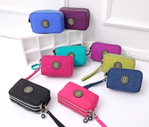 Detailed view of eight colorful multi-layered zipper purses with wrist straps