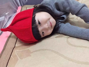 Detail of red pointed knit hat for kids made of soft yarn with a unique windmill top shape