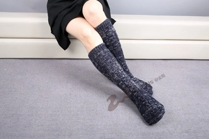 Detailed close-up of thick knitted Christmas socks with navy blue marble yarn texture