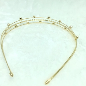 Close-up of golden double-layered headband with white pearls and sparkling rhinestones