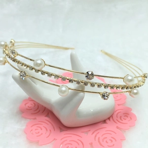 Detail of a multi-layer gold headband with imitation pearls and rhinestones on a hand stand