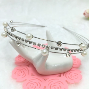 Detail shot of a layered silver headband featuring sparkling rhinestones and white pearls