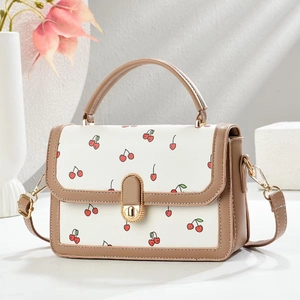Detail of cherry print handbag showing gold twist lock and khaki leather trim