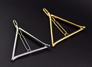 Detailed view of geometric triangle metal hair clips in polished gold and silver finishes