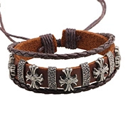 Detail of multilayer brown leather bracelet featuring vintage silver metal cross charms