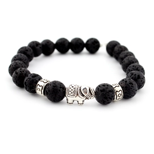 Macro detail of black lava stone beads and silver elephant charm on a beaded bracelet
