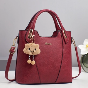 Deep red textured leather handbag with a plush cloud charm and gold hardware accents