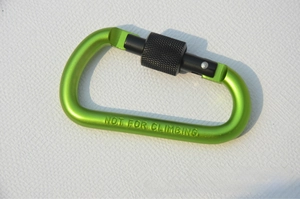 Macro view of green aluminum D-ring carabiner with black locking screw and safety warning