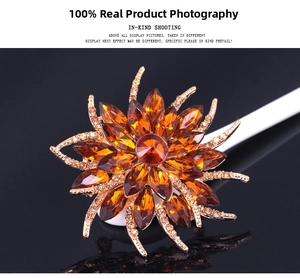 Macro view of crystal floral brooch with amber stones on a black reflective surface