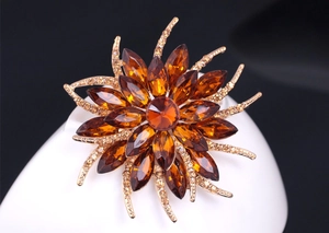 Macro view of amber crystal sunflower brooch with golden radiating lines and tiny diamonds