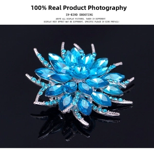 Macro detail of silver floral brooch with light blue crystals on black mirror surface