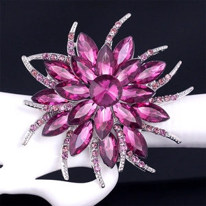 Exquisite purple crystal flower brooch on a white stand against a black background