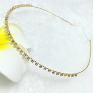 Close-up of minimalist gold metal headband with sparkling clear rhinestones on white faux fur
