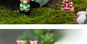 Nahaufnahme von zwei Mini-Weihnachtsbären aus Harz mit Sternen auf grünem Moosgrund