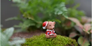 Detail einer Miniatur-Weihnachtsbär-Figur mit rotem Hut in einer Moos-Mikrolandschaft