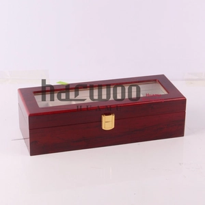 Macro detail of red-brown wood watch box with clear window and six slots with gold latch