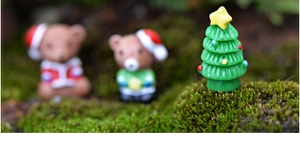 Makroaufnahme von Miniatur-Weihnachtsbaum und süßen Bären auf natürlichem Moos