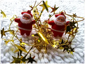 Detail of Santa Claus hanging ornaments with red plush bodies and gold strings on white carpet