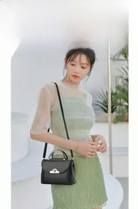 Dettaglio mini borsa a tracolla nera con texture intrecciata e manico in oro metallo
