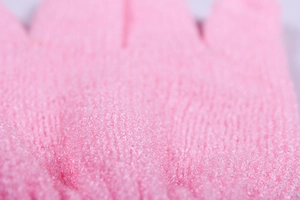Macro shot of pink exfoliating bath glove showing high-density nylon woven texture