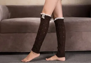 Detail of dark brown knitted leg warmers with delicate lace trim and white button accents