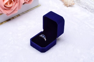 Close-up of three blue gemstones ring in a royal blue velvet jewelry box with rose