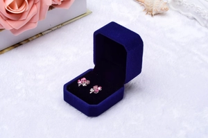 Blue velvet jewelry box with floral silver earrings on white plush background