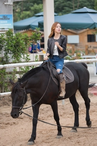 Close-up of a women's black slim fit faux leather jacket with zip closure on horseback