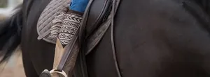 Detail of bohemian knit leg warmers with fringes styled over denim jeans and boots