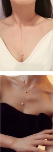 Detail showing elegant gold Y-shaped necklace with pearl pendant on model neck