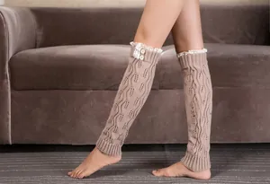 Detail of cable knit leg warmers with delicate white lace trim and white buttons