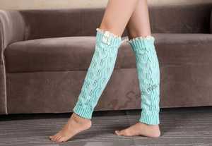 Close-up of mint green knitted leg warmers with delicate white lace trim and buttons