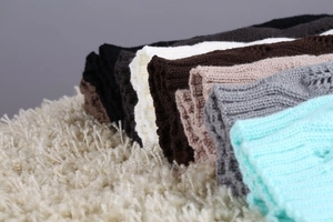 Detailed knit texture of multi-color vertical ribbed leg warmers on a plush carpet