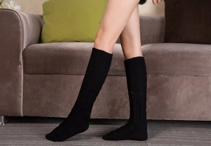 Detailed close-up of cable-knit texture on black winter leg warmers for home comfort