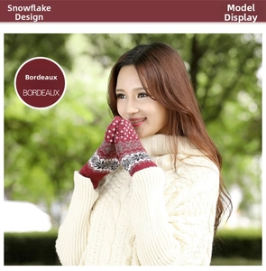 Detail of knitted bordeaux winter gloves with white snowflake pattern in outdoor setting