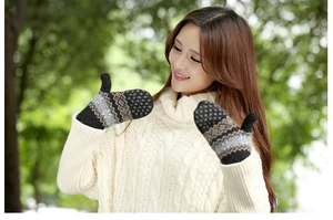 Close-up of thick knitted mittens with snowflake patterns worn in a winter forest