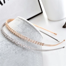 Detail of silver and rose gold rhinestone headbands on a grey velvet display stand