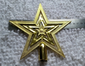 Golden hollow Christmas tree star topper with base, 17cm width, on white plush fabric