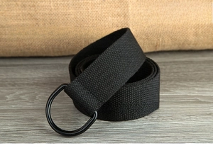 Detail of black canvas belt with double D-ring metal buckle on rustic background