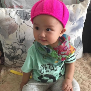 Flat lay of pink knit hat with green t-shirt and floral scarf for infants