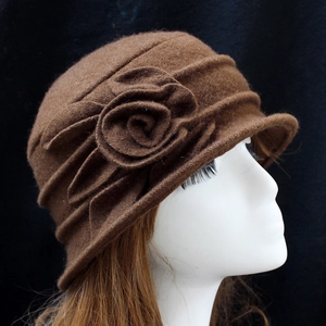 Detail of wool cloche hat with textured pleats and elegant felt flower decoration
