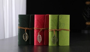 Detail of vintage embossed leather journals with leaf pendants and leather straps