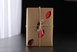 Detail of vintage kraft paper gift box with leaf cut-outs and rustic twine ribbon